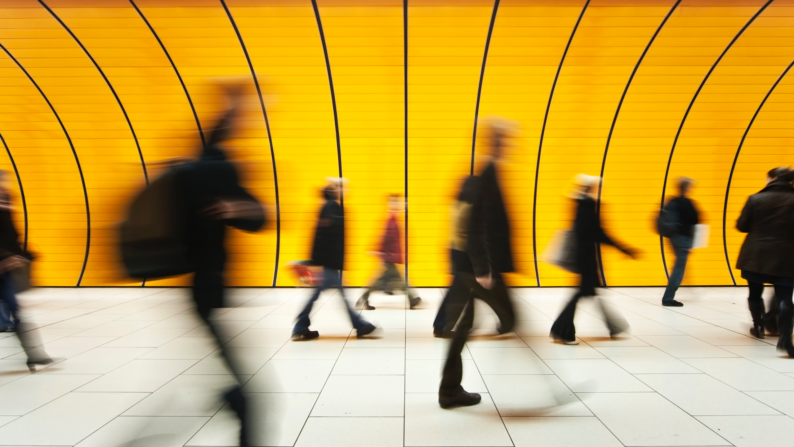 Blurred people walking through a yellow tunnel